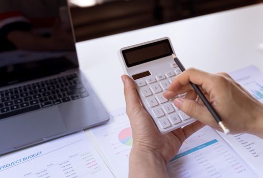 Hand holding pencil and press button calculator. Financial and tax systems concept.