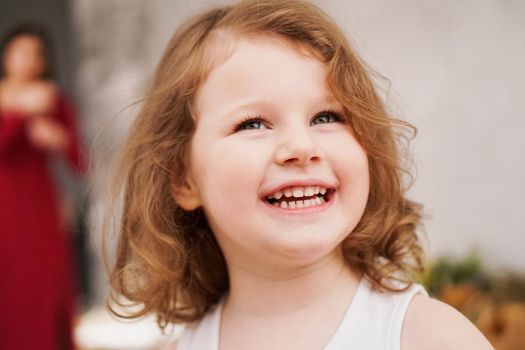 Portrait of a happy three-year-old girl. The blonde-haired child laughs.