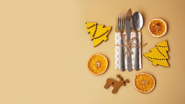 Setting of table with dry orange and wooden christmas figurines on gold background - top view