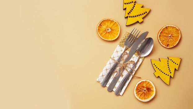 Setting of table with dry orange and wooden christmas figurines on gold background