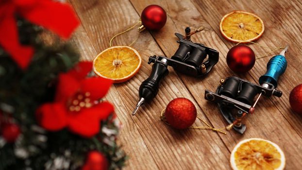 Tattoo machines on a christmas background - christmas decor with tree on a blsck background