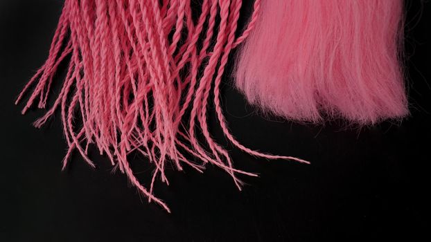 Pink kanekalon hangs and braids on a black background - tips close up