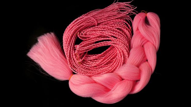 Pink kanekalon hangs and braids on a black background