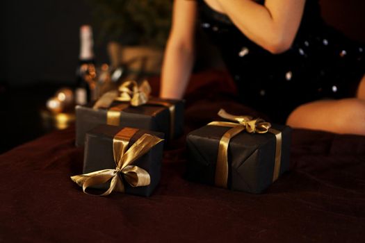 Woman with gifts in black boxes with a gold ribbon. Closeup photo