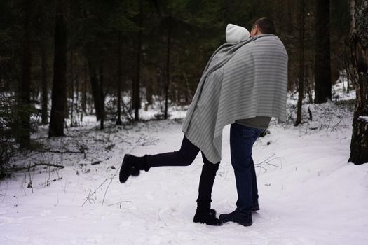 Couple among high fir trees with first snow. Winter holidays, Christmas