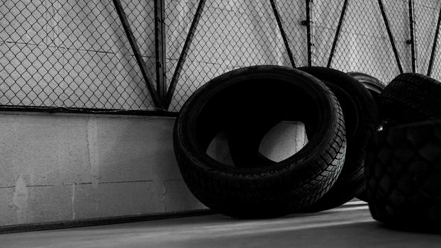 Tire warehouse. Four tires on the concrete floor. Black mesh on the wall. Brutal photo