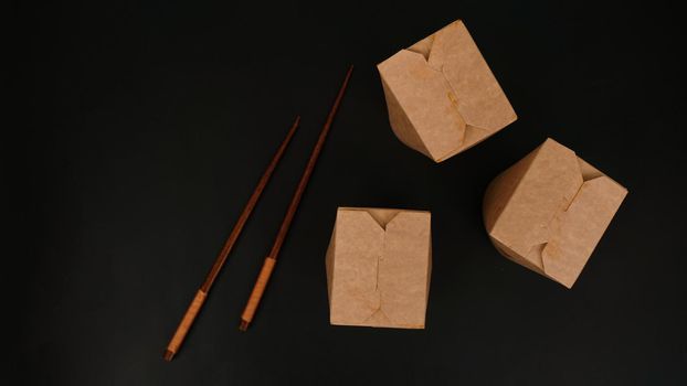 Brown paper cardboard food container on black background. Asian food delivery. Wok packaging