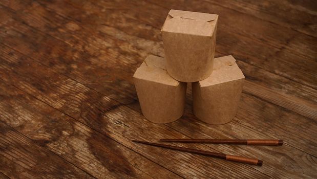 Brown paper cardboard food container on wooden background. Asian food delivery. Wok packaging