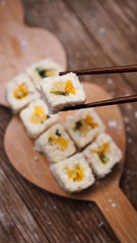 Sushi delivery. Sweet rolls made from rice, pineapple, kiwi and mango. Rolls on a wooden background. Wooden sticks for sushi.