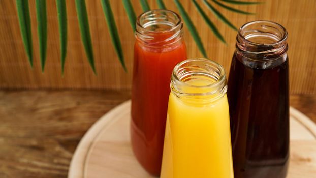 Glass bottles of fresh healthy juice on wooden background. Multi-colored juices. Summer photo and healthy lifestyle, vitamins