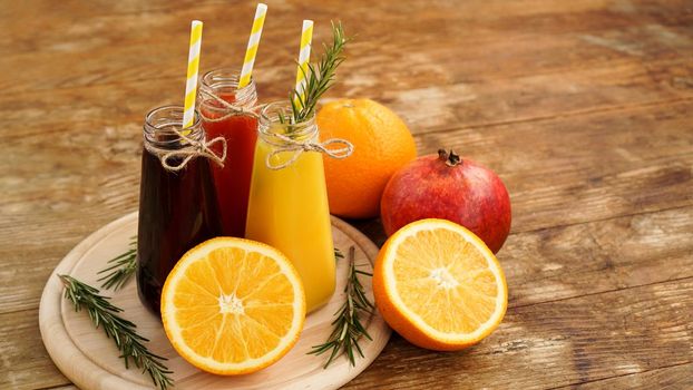 Home made lemonade in little bottles. Multicolored juices and fruits on wooden background