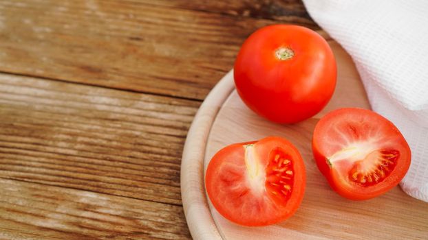Whole and cut tomato on a wooden board for slicing. Rustic style and wood background. Vegetables and healthy eating. Ingredients for tomato juice