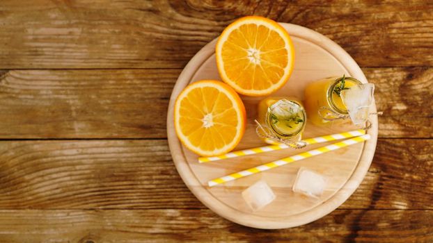 Orange juice on a wooden tray. Sliced orange and ice cubes. Snack at the resort, coolness on a hot summer day. Top view