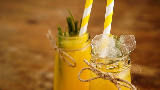 Bottle of orange juice with ice cubes, selective focus. Wooden background.