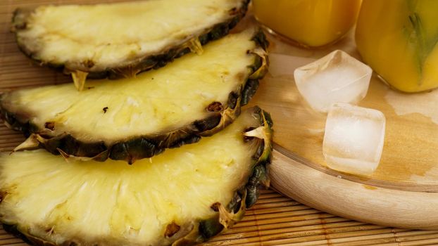 Fresh pineapple slices and and ice cubes on a wooden background. Fresh pineapple juice on the background. Cool on a hot summer day. Snack at resort