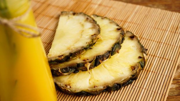 Bottles of pineapple juice on a wooden table. Yellow drink and fresh pineapple. Snack at the resort. Summer photo