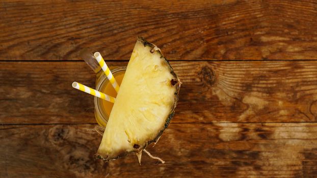 Pineapple juice on a wooden background. A glass jar with juice and a slice of fresh pineapple. Exotic fruits and healthy juice with vitamins
