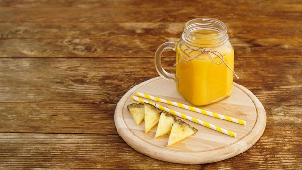 Bottles of pineapple juice on a wooden table. Yellow drink and fresh pineapple. Snack at the resort on a wooden tray. Summer photo