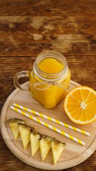 Bottles of pineapple juice on a wooden table. Yellow drink and fresh pineapple. Snack at the resort. Summer photo