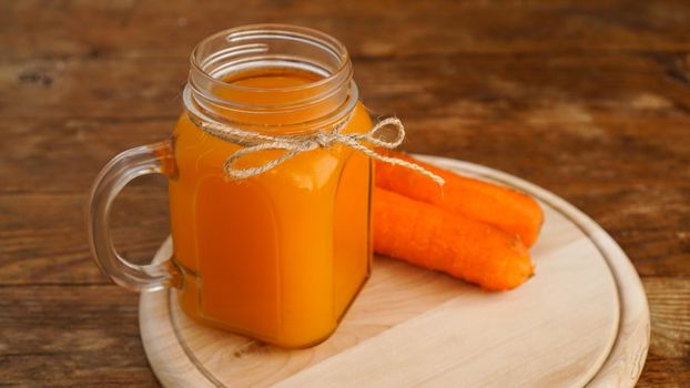 Carrot juice in a glass jar on a wooden background