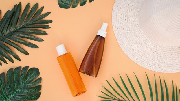 Sun cream, sun hat, lotion bottle on soft orange background. Sun protection. Summer time and holiday