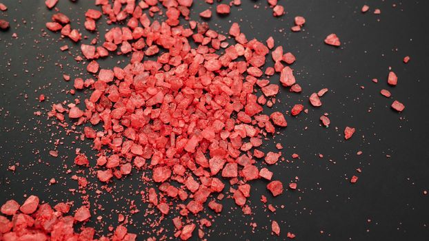 Salt isolated on a black background. A pile of red salt. Large crystalline salt. Beauty and health concept