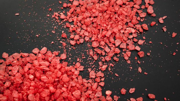 Salt isolated on a black background. A pile of red salt. Large crystalline salt. Beauty and health concept