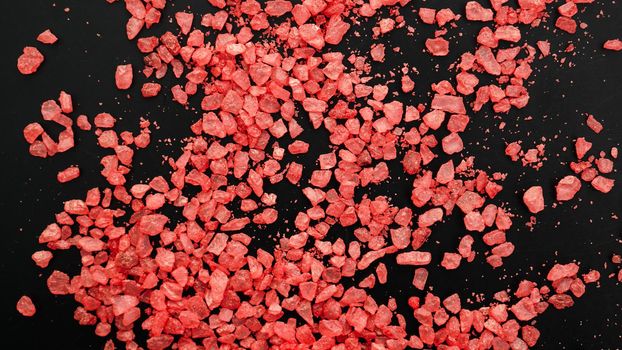 Salt isolated on a black background. A pile of red salt. Large crystalline salt. Beauty and health concept