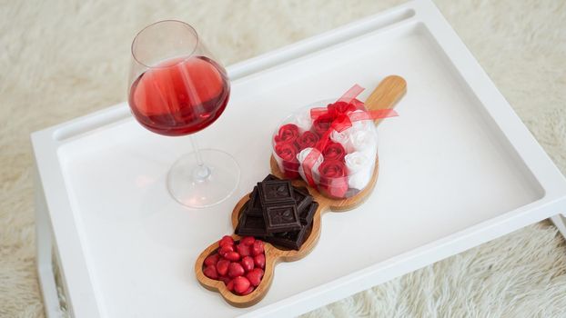 Breakfast for girlfriend. Valentines Day Morning. Wine and sweets on a white tray. Breakfast in bed.