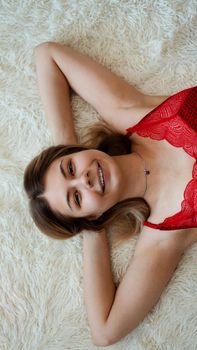 Beautiful young woman lying on a white shaggy blanket. View from above.