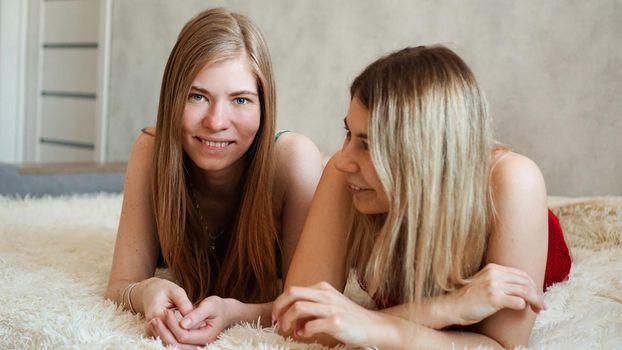 Happy friends lying in bed and talking and laughing