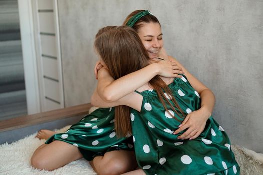 Lifestyle, friendship and people concept - two beautiful girls dressed in pajamas hugging and smiling