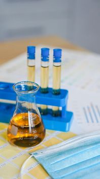 Flask and test tubes with urine on medical color schemes. The concept of laboratory analyzes, ph control. Vertical photo