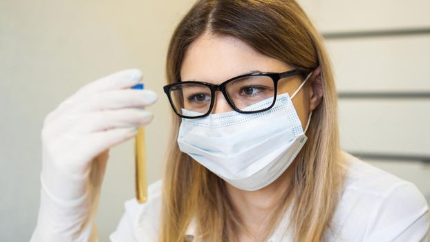 A woman holds a test tube with a urine test. Diagnostics and analysis concept. Health concept