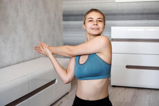 Fitness, home and diet concept. Smiling girl streching on floor at home. Stretching the arms and shoulders