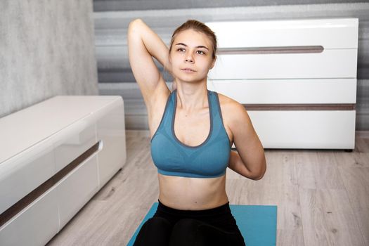 Young athletic woman doing stretching before home workout. Fitness trainer at home