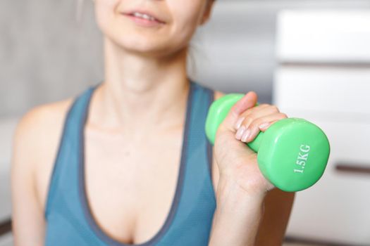 Sport and recreation concept - sporty woman hand with light green dumbbell