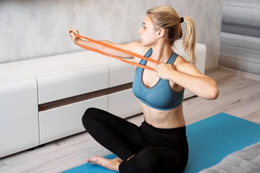 Woman at home trying to lose weight and have training with elastic band in her hands
