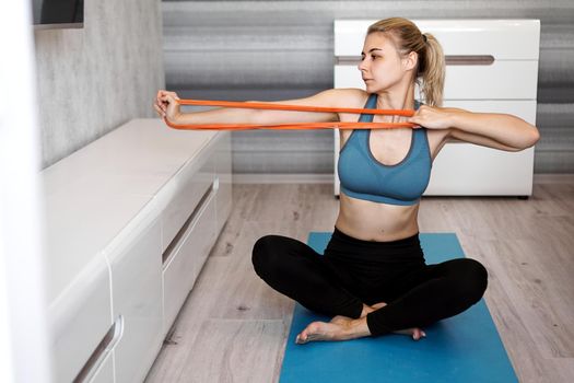 Woman at home trying to lose weight and have training with elastic band in her hands