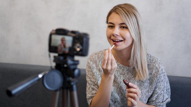 A beauty blogger or video blogger tells and shows subscribers how to do makeup. Young woman paints lips