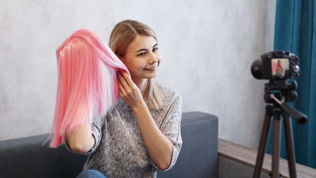 Woman blogger records video. She talks about haircuts and shows a pink wig. Stylist and fashion consultant recording the lecture