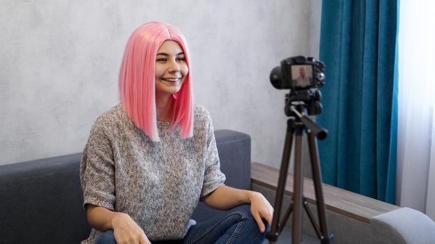 Young and smart. Beautiful young woman with pink hair in casual wear while recording video blod