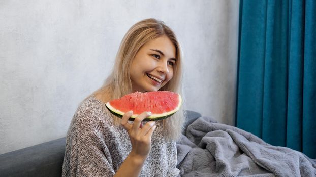 Young attractive woman eating watermelon. Woman at home in a cozy interior