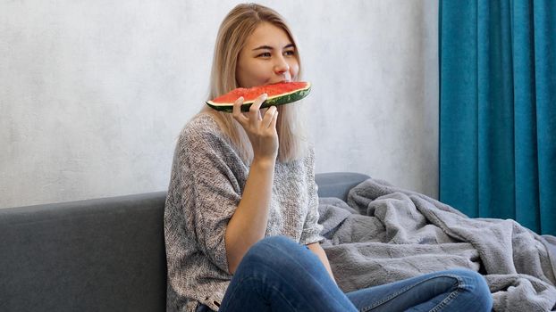 Young attractive woman bites a piece of watermelon. Woman at home in a cozy interior