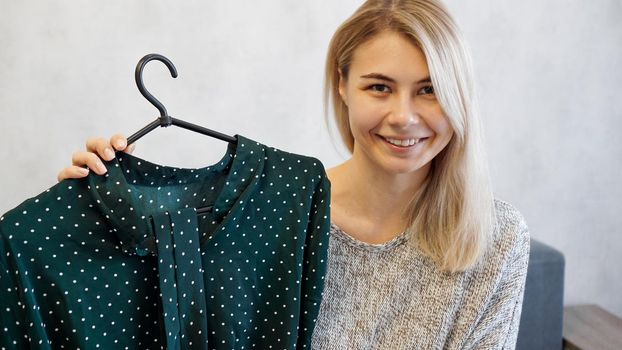 Beautiful woman shows a dress on a hanger. She talks about fashion and records a video blog