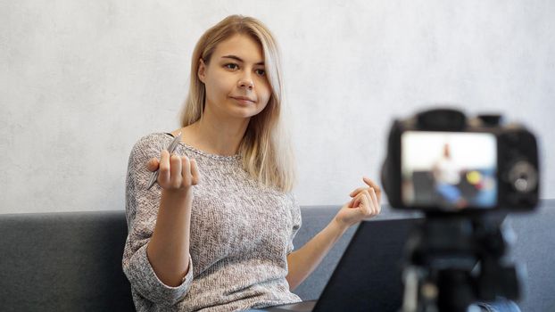 Young female blogger with laptop and pen looking at camera. She talks about business or records a lecture for students