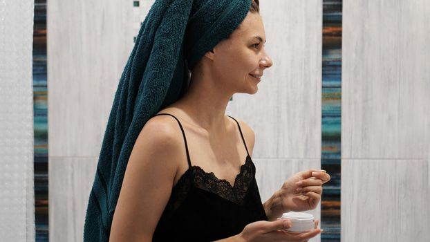 Happy woman in the bathroom with a towel on her head