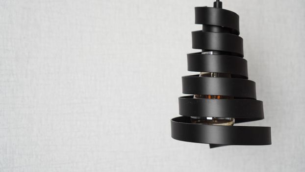 A modern loft chandelier made of black metal spiral in a stylish white interior