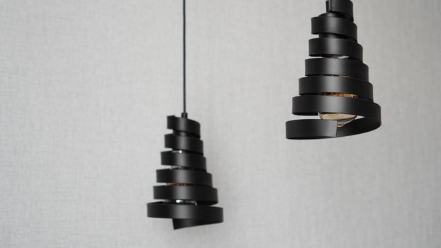 A modern loft chandelier made of black metal spiral in a stylish white interior