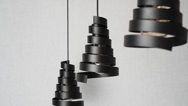 A modern loft chandeliers made of black metal spiral in a stylish white interior